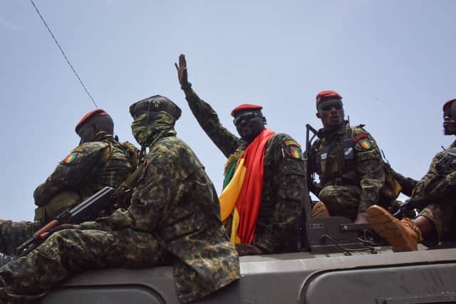 TOPSHOT - Lieutenant Colonel Mamady Doumbouya (C), head of the Armys special forces and coup leader, waves to the crowd as he arrives at the Palace of the People in Conakry on September 6, 2021, ahead of a meeting with the Ministers of the Ex-President of Guinea, Alpha Conde. - Lieutenant Colonel Mamady Doumbouya, the leader of the latest coup in Guinea, is a highly educated, combat-hardened soldier who once served in France’s Foreign Legion. Doumbouya’s special forces on September 5, 2021 seized Alpha Conde, the West African state’s 83-year-old president, a former champion of democracy accused of taking the path of authoritarianism. (Photo by CELLOU BINANI / AFP) (Photo by CELLOU BINANI/AFP via Getty Images)