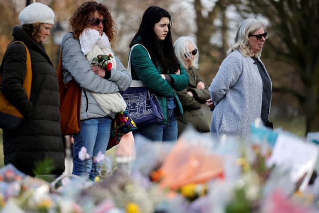 Well-wishers reflect alongside floral tributes in honour of Sarah Everard. Photo by TOLGA AKMEN/AFP via Getty Images