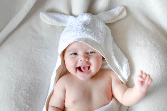 Adorable newborn baby wrap by white rabbit towel with smiling face (Pic from Shutterstock)