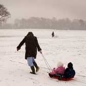  A woman pulls children on a sled up a snow-covered hill in Liverpool.