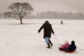  A woman pulls children on a sled up a snow-covered hill in Liverpool.