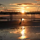People walk with a dog along the beach at sunset, near Southport Pier. Image: PAUL ELLIS/AFP via Getty Images