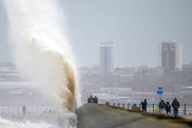 People view the waves created by high winds and spring tides hitting the sea wall at New Brighton promenade on February 17, 2022 in Liverpool, England