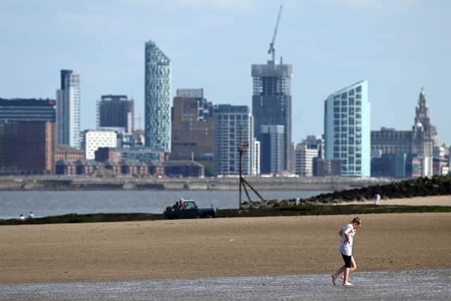 The Liverpool skyline is seen across the River Mersey as people walk on the beach at New Brighton.   (Photo by PAUL ELLIS / AFP) (Photo by PAUL ELLIS/AFP via Getty Images)