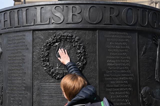 People touch the Hillsborough Memorial Monument as the city observes a minute’s silence at 3.06pm in Liverpool. Photo: PAUL ELLIS/AFP via Getty Images