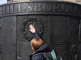 People touch the Hillsborough Memorial Monument as the city observes a minute’s silence at 3.06pm in Liverpool. Photo: PAUL ELLIS/AFP via Getty Images