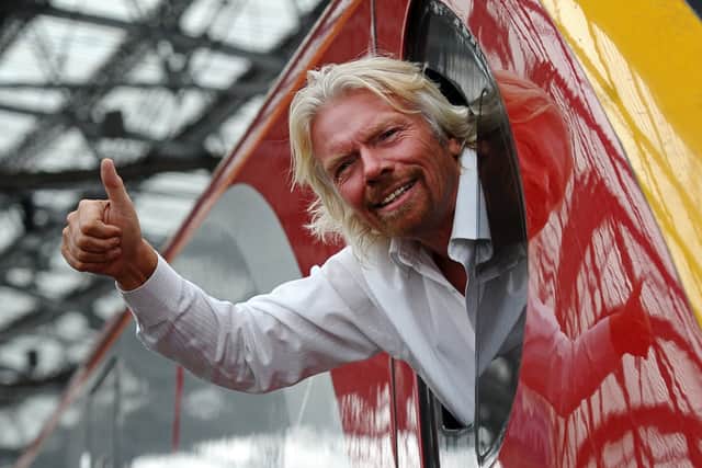 British entrepreneur Sir Richard Branson leans out of the window of the driver’s cab on board a Virgin Pendolino train at Lime Street Station in Liverpool in 2012. Photo: Paul Ellis/AFP via Getty Images.
