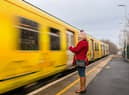 A  woman on her phone as a Merseyrail train approaches. Image: Gabriel - stock.adobe.com