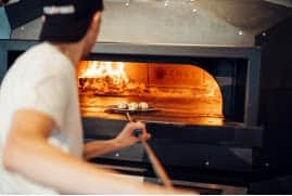 Pizza is cooked in a wood burning oven.