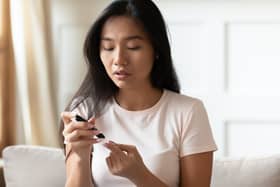 A woman uses a glucose meter to measure her blood sugar level at home. Image: fizkes - stock.adobe.com