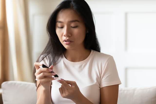 A woman uses a glucose meter to measure her blood sugar level at home. Image: fizkes - stock.adobe.com