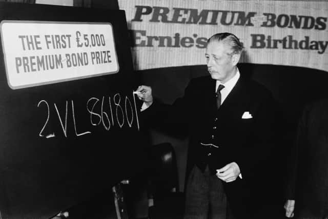 British Prime Minister Harold Macmillan (1894 - 1986) writes the number of the first winner of 5000 pounds in the Premium Bond prize draw