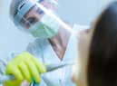 <p>Female dentist with face mask and visor as coronavirus safety precaution checkup dental health of young woman. Image: Robert Petrovic - stock.adobe.co</p>