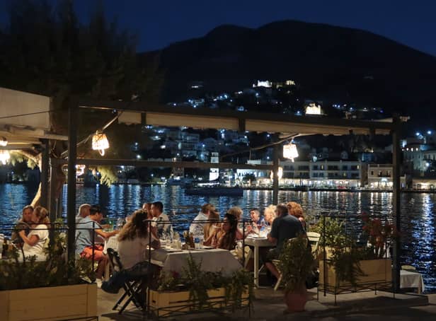<p>People eat dinner at Tholos taverna on the waterfront in the town of Ano Symi</p>