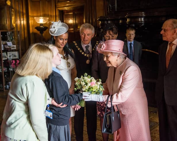 Queen Elizabeth II receives flowers from a student at St Vincent’s School in 2016.