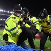 A fan is arrested on the pitch by police officers during the Premier League match between Everton and Liverpool at Goodison Park on December 01, 2021