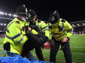 A fan is arrested on the pitch by police officers during the Premier League match between Everton and Liverpool at Goodison Park on December 01, 2021
