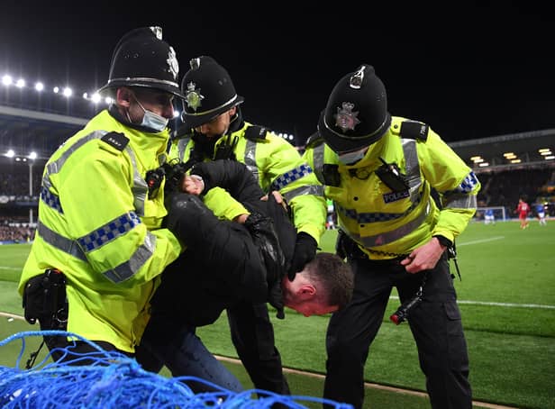 <p>A fan is arrested on the pitch by police officers during the Premier League match between Everton and Liverpool at Goodison Park on December 01, 2021</p>