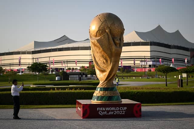 A man takes a picture of a FIFA World Cup trophy replica in front of the Al-Bayt Stadium in al-Khor on November 10, 2022, ahead of the Qatar 2022 FIFA World Cup football tournament. (Photo by Kirill KUDRYAVTSEV / AFP) (Photo by KIRILL KUDRYAVTSEV/AFP via Getty Images)