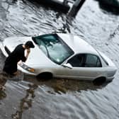 A man makes a phone call next to his car submerged in flood water. Image: bartsadowski - stock.adobe.com