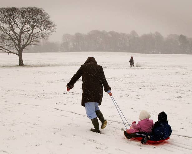 A woman pulls children on a sled up a snow-covered hill in Liverpool. Photo: AFP via Getty