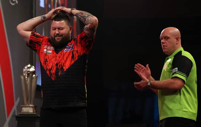 England's Michael Smith (L) reacts after winning the PDC World Darts Championship final match against Netherlands' Michael van Gerwen at Alexandra Palace in London on January 3, 2023. (Photo by Adrian DENNIS / AFP) (Photo by ADRIAN DENNIS/AFP via Getty Images)