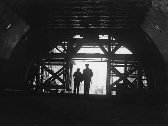 Two workmen stand framed in the entrance to the nearly-completed Mersey Tunnel, which connects Birkenhead and Liverpool. 