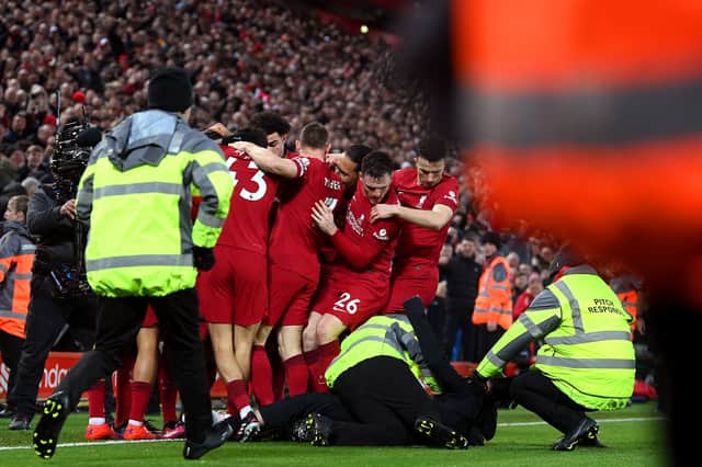 A pitch invader is tackled by stewards after colliding with Andrew Robertson of Liverpool as players of Liverpool celebrate after Roberto Firmino of Liverpool ( Obscured ) scores the team's seventh goal during the Premier League match between Liverpool FC and Manchester United at Anfield on March 05, 2023 in Liverpool, England. (Photo by Michael Regan/Getty Images)
