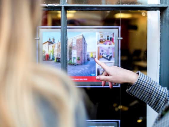 Couple looking and pointing at a property advert in the window of an estate agents. Image:F-Stop Boy - stock.adobe.com