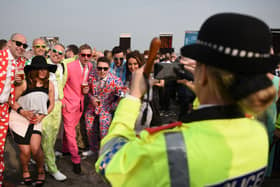 A police officer takes a photograph of racegoers on ‘Ladies Day’ of the Grand National Festival horse race meeting at Aintree Racecourse. Image: OLI SCARFF/AFP via Getty Images