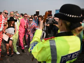 A police officer takes a photograph of racegoers on ‘Ladies Day’ of the Grand National Festival horse race meeting at Aintree Racecourse. Image: OLI SCARFF/AFP via Getty Images