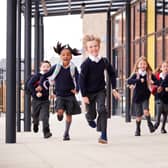 Primary school kids, wearing school uniforms and backpacks, running. Image: Monkey Business - stock.adobe.co