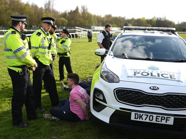 An animal rights protester is apprehended by police officers ahead of the Grand National. 