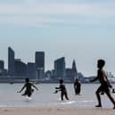 People enjoy the warm weather and sunshine on New Brighton beach and promenade with the Liverpool skyline behind. Image: Christopher Furlong/Getty Images