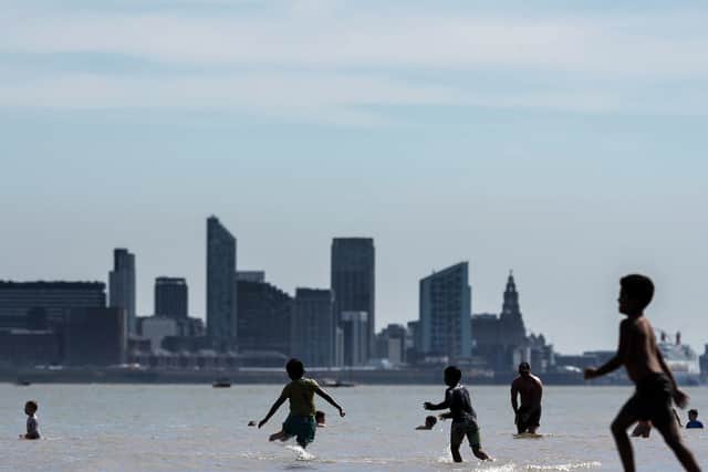 People enjoy the warm weather and sunshine on New Brighton beach and promenade with the Liverpool skyline behind. Image: Christopher Furlong/Getty Images