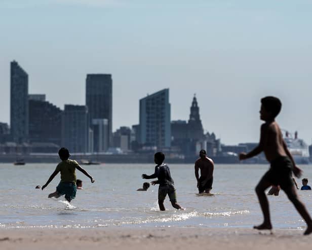 People enjoy the warm weather and sunshine on New Brighton beach and promenade with the Liverpool skyline behind. Image: Christopher Furlong/Getty Image