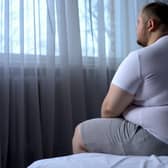 A heavy man sitting on bed at home. Image: motortion - stock.adobe.com
