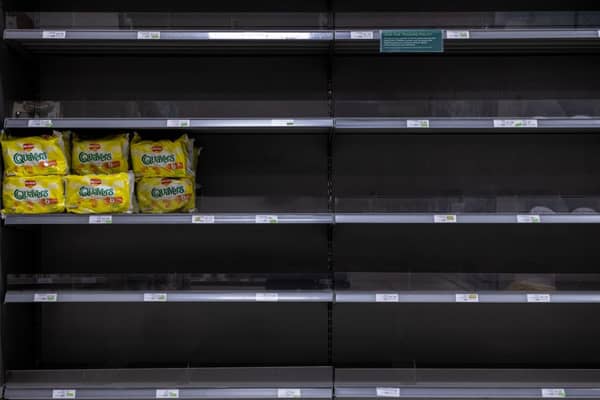 Walkers Quavers crisps stand alone on an otherwise empty shelf. 
