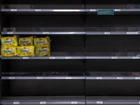 Walkers Quavers crisps stand alone on an otherwise empty shelf. 