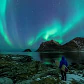 A surfer looks at Northern Lights in Utakleiv, northern Norway (Photo: OLIVIER MORIN/AFP via Getty Images)