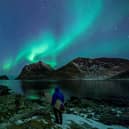 A surfer looks at Northern Lights in Utakleiv, northern Norway (Photo: OLIVIER MORIN/AFP via Getty Images)
