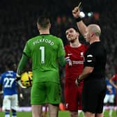 Referee Simon Hooper shows a yellow card to Jordan Pickford of Everton and Andy Robertson of Liverpool