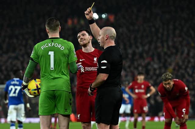 Referee Simon Hooper shows a yellow card to Jordan Pickford of Everton and Andy Robertson of Liverpool