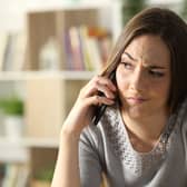 A suspicious woman calling on a phone sitting at home. Image: PheelingsMedia - stock.adobe.com