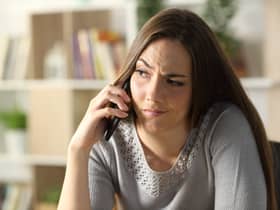 A suspicious woman calling on a phone sitting at home. Image: PheelingsMedia - stock.adobe.com