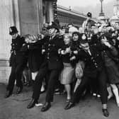 Police keeping back a crowd of young fans outside Buckingham Palace, London, as pop group the Beatles receive their MBEs.  (Photo by Ted West/Central Press/Hulton Archive/Getty Images)