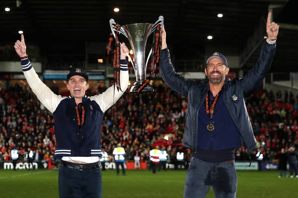 Rob McElhenney and Ryan Reynolds, Owners of Wrexham celebrate with the Vanarama National League trophy as Wrexham win the Vanarama National League and are promoted to the English Football League after victory in the Vanarama National League match between Wrexham and Boreham Wood at Racecourse Ground on April 22, 2023 in Wrexham, Wales. (Photo by Jan Kruger/Getty Images)