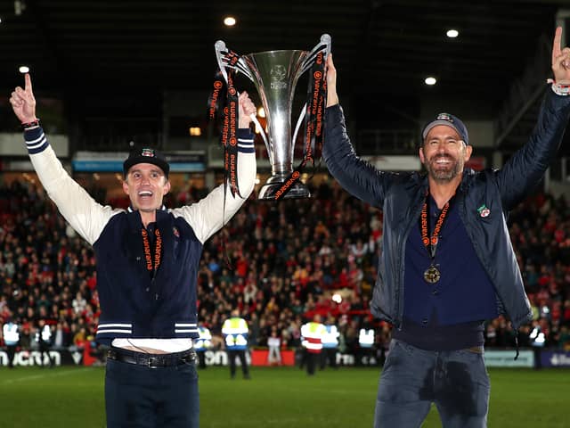 Rob McElhenney and Ryan Reynolds, Owners of Wrexham celebrate with the Vanarama National League trophy as Wrexham win the Vanarama National League and are promoted to the English Football League after victory in the Vanarama National League match between Wrexham and Boreham Wood at Racecourse Ground on April 22, 2023 in Wrexham, Wales. (Photo by Jan Kruger/Getty Images)