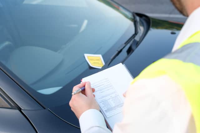 A traffic warden gives a ticket fine for a parking violation. Image: Paolese/stock.adobe.com