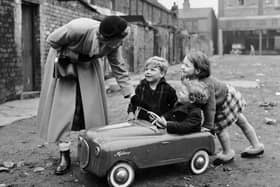 Miss Peggy Robertshaw stops to talk to three children as she walks her daily 12 miles around Liverpool, testing shoes. Peggy works for Dunlop of Speke, and since 1927 has covered over 72,000 miles. Image: Ken Harding/BIPs/Getty Images